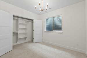 Unfurnished bedroom with light carpet, a chandelier, and a closet