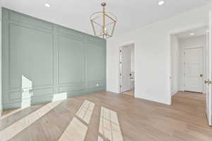 Unfurnished dining area featuring light wood-style flooring, recessed lighting, and a chandelier