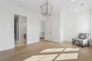 Unfurnished room featuring light wood-type flooring, recessed lighting, and a chandelier