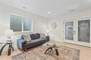 Living room with light wood-type flooring, french doors, and recessed lighting