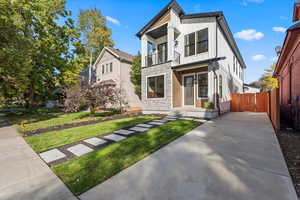 View of front of home featuring a balcony, board and batten siding, stone siding, and a front yard