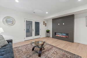 Living room featuring french doors, recessed lighting, light wood-style flooring, and a fireplace