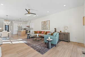 Living area featuring light wood-style flooring, ceiling fan, recessed lighting, and a chandelier
