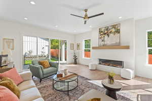 Living room featuring a glass covered fireplace, wood finished floors, recessed lighting, and a ceiling fan
