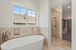 Full bathroom featuring a freestanding tub, a shower stall, tile walls, wainscoting, and recessed lighting