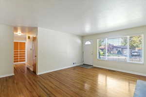 Unfurnished living room featuring wood finished floors and a textured ceiling