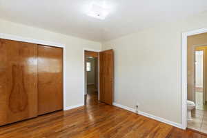 Unfurnished bedroom featuring wood-type flooring, a closet, and connected bathroom