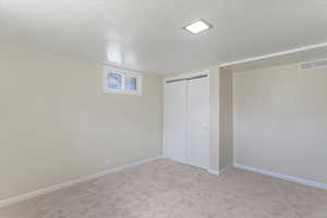 Unfurnished bedroom with a textured ceiling, carpet flooring, and a closet
