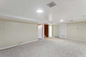 Finished basement with stairs and light carpet