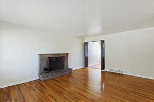 Unfurnished living room with a brick fireplace and wood finished floors