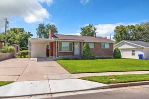 Ranch-style house with brick siding, driveway, a carport, and a chimney