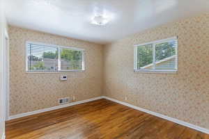 Empty room with wood finished floors and wallpapered walls