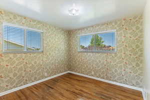 Spare room featuring wood-type flooring and wallpapered walls