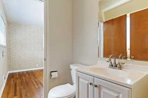 Bathroom with vanity, dark wood-style floors, plenty of natural light, and wallpapered walls
