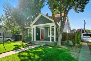 Bungalow-style home featuring covered porch, a front lawn, and a chimney