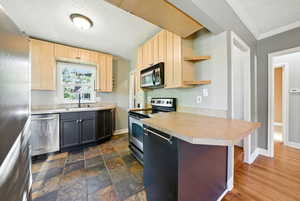Kitchen with appliances with stainless steel finishes, light countertops, open shelves, crown molding, and light brown cabinetry