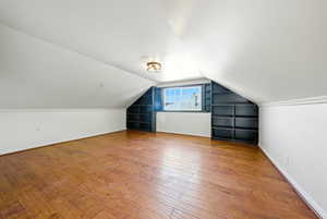 Additional living space featuring vaulted ceiling, light wood-style flooring, and built in shelves