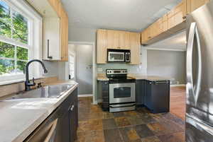Kitchen with stainless steel appliances, light countertops, dark stone finish flooring, a peninsula, and a textured ceiling
