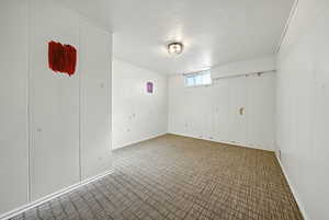 Empty room featuring baseboards and dark carpet