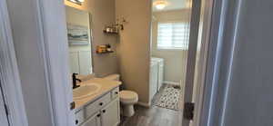 Full bathroom with vanity, dark wood-type flooring, and washer and dryer