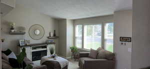 Living area with a textured ceiling, wood finished floors, and a glass covered fireplace