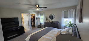 Bedroom featuring carpet floors, a textured ceiling, a spacious closet, and ceiling fan