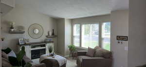 Living area featuring a textured ceiling, a glass covered fireplace, and wood finished floors