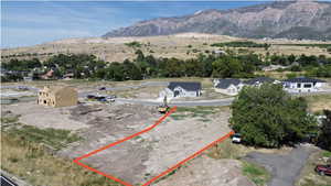 Aerial view of property and surrounding area with a mountain backdrop and property parcel outlined