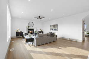 Living area with light wood-style floors, recessed lighting, a glass covered fireplace, and ceiling fan