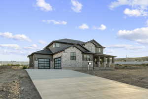 View of front of house featuring stone siding, covered porch, concrete driveway, and a garage