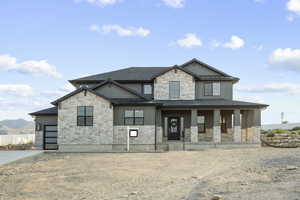 Craftsman-style house with a standing seam roof, a porch, stone siding, a metal roof, and board and batten siding