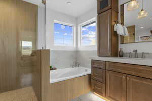 Full bath with a bath, vanity, healthy amount of natural light, and a tile shower