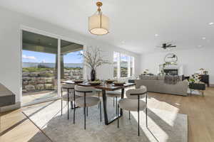 Dining space featuring light wood finished floors, a glass covered fireplace, ceiling fan, and recessed lighting