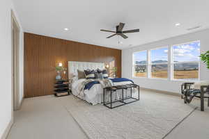 Carpeted bedroom with wooden walls, a mountain view, a ceiling fan, and recessed lighting