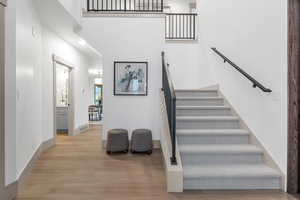 Staircase with wood finished floors and a towering ceiling