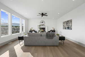 Living room with a glass covered fireplace, wood finished floors, recessed lighting, a water view, and ceiling fan