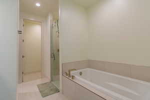Full bathroom with light tile patterned flooring, a garden tub, a shower stall, and recessed lighting