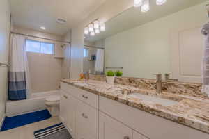 Bathroom with shower / tub combo, double vanity, and light tile patterned floors