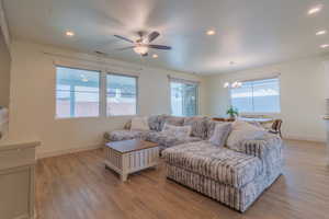 Living room featuring light wood-type flooring, a ceiling fan, recessed lighting, and a chandelier