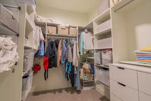 Walk in closet featuring light colored carpet