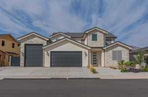 View of front facade featuring stone siding, an attached garage, concrete driveway, and stucco siding