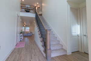 Stairs featuring wood finish floors, ceiling fan, recessed lighting, and a towering ceiling