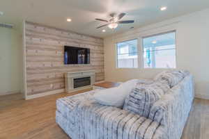 Living area with recessed lighting, a glass covered fireplace, light wood-style floors, and ceiling fan