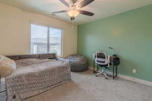 Carpeted bedroom with baseboards and a ceiling fan