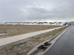 View of asphalt road featuring curbs, sidewalks, street lighting, and a residential view