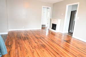 Unfurnished living room with a fireplace with raised hearth and light wood-style flooring