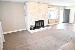 Unfurnished living room with a stone fireplace, carpet, and recessed lighting
