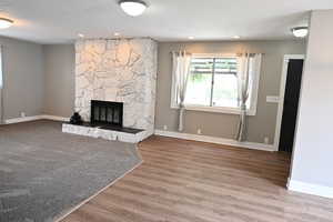 Unfurnished living room with a fireplace, a textured ceiling, light wood-type flooring, and recessed lighting