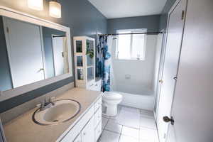 Bathroom with shower / tub combo with curtain, vanity, and light tile patterned floors