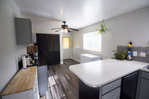 Kitchen featuring gray cabinets, dark wood-type flooring, black dishwasher, and a peninsula